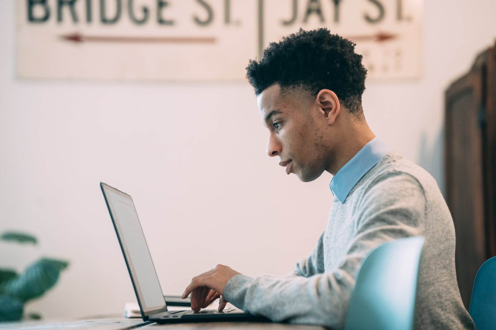 ethnic young freelancer using laptop