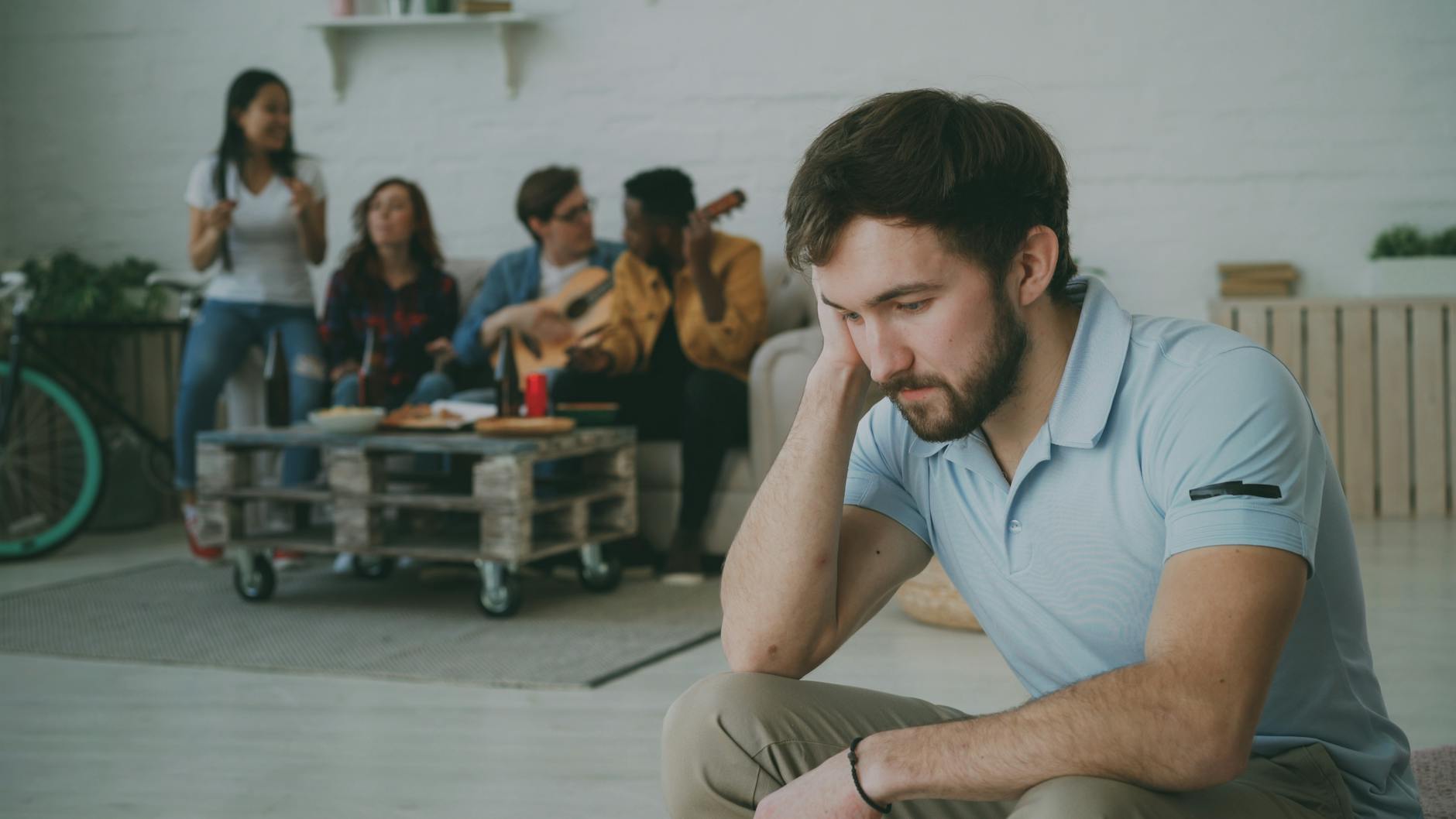 lonely man sitting amidst social gathering